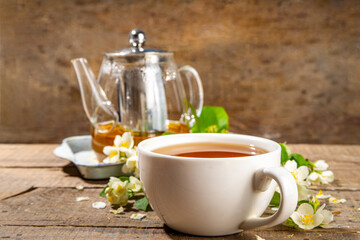 Herbal jasmin flower tea. Jasmine green tea in glass teapot and white tea cup, with fresh jasmin blossom
