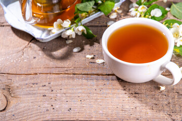 Herbal jasmin flower tea. Jasmine green tea in glass teapot and white tea cup, with fresh jasmin blossom