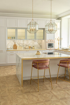 a close view of the white stylish kitchen with a cooking island in the luxurious interior of a modern apartment in light colors with stylish furniture.