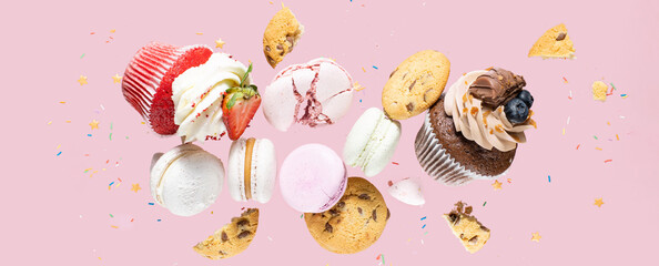 Confectionery, donuts, cupcakes, cookies, macarons flying over pink background, panoramic view...