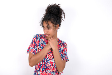 Sad Young African American woman wearing colourful dress over white wall feeling upset while spending time at home alone staring at camera with unhappy or regretful look.