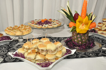froid buffet table with canapes and savory snacks with meats fruits cheeses with decorations of carved vegetables in event hall