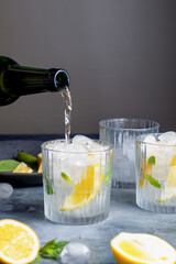 pouring a lemonade in the glass. citrus lemonade with mint and lemon in the glass with ice cubes.