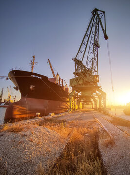 cargo ship bulk carrier is loaded with grain of wheat in port at sunset