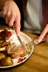 a man's hands cut meat on a restaurant plate
