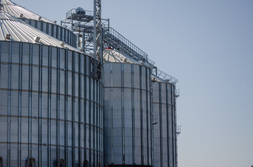 Construction of new cylindrical silos for grain storage. Metal silos are made of corrugated metal. A row of hand winches lifts the metal structure upward. Agribusiness. Grain exports. © Mikhail