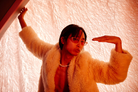 Waist up shot of male vogue dancer looking at camera in red neon light in nightclub, copy space