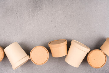 Sustainable food packaging concept. Different disposable kraft paper food containers for food to go with paper cap over gray concrete table background with copy space, mockup image