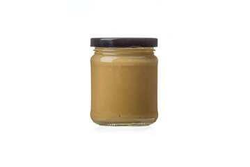 Closed glass jar with Dijon mustard on a white background.