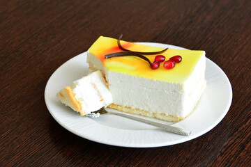 slice of cream lemon cake with teaspoon isolated on white plate, close-up