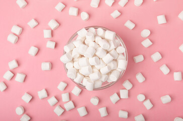 Marshmallows on a pink background in a glass bowl. White marshmallow flat lay. Sweets and snacks for a snack. Chewing candies close-up. Copy space. Place for text. Winter food concept.