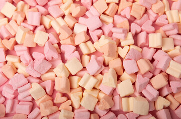 Fruit marshmallows in bulk on a pink background.Sweets and snacks for a snack.Chewy candy close-up.Space for copy.Place for text.