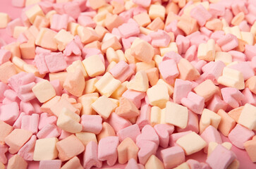 Fruit marshmallows in bulk on a pink background.Sweets and snacks for a snack.Chewy candy close-up.Space for copy.Place for text.