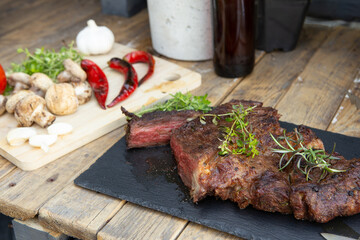 Grilled beef steak on wooden table top. Healthy food concept. Beef cut outdoors, garden kitchen, bbq grill patio