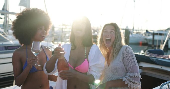 Happy multiracial female friends having fun drinking champagne at boat party outdoor - Summer and vacation concept 