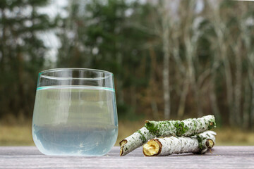 Birch sap in a glass. Birch earrings. Birch branches. Collection of birch sap.