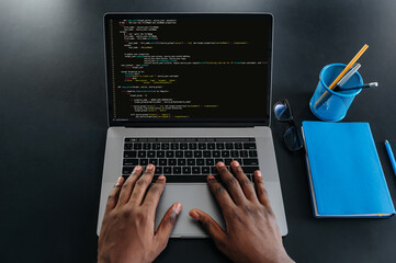 Top view of male african american hands on a laptop keyboard, IT specialist, programmer, sits in a...
