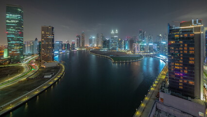 Cityscape of skyscrapers in Dubai Business Bay with water canal aerial night timelapse