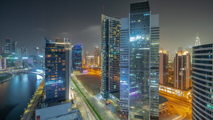 Cityscape of skyscrapers in Dubai Business Bay with water canal aerial night timelapse