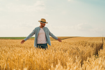 Happy farmer is standing in his growing wheat field.