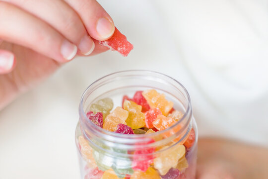Female hands holding a glass jar of gummy bears close up. Childrens sweets.