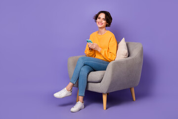 Fototapeta na wymiar Portrait of attractive cheerful girl sitting in chair using device gadget app 5g isolated over violet lilac color background