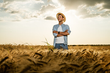 Naklejka na ściany i meble Happy farmer is standing in his growing barley field.