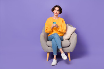 Fototapeta na wymiar Portrait of attractive minded girl sitting using gadget chatting creating post smm isolated over violet lilac color background