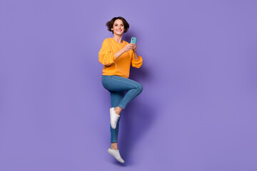 Fototapeta na wymiar Full length body size view of attractive cheerful girl jumping using gadget blog 5g smm isolated over violet lilac color background