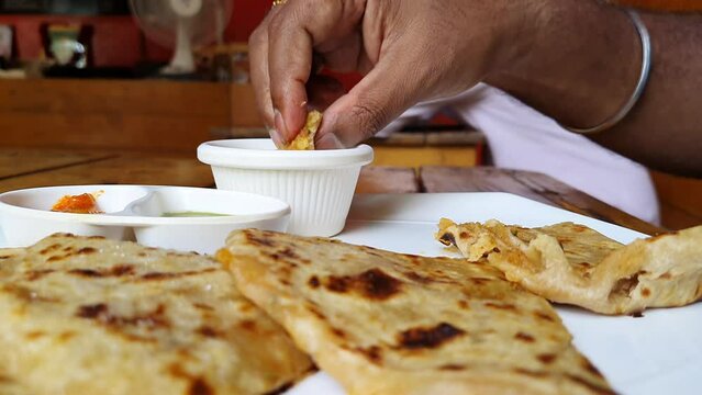 close up of eating aloo paratha / potato stuffed flat bread