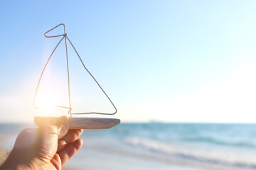 Man holding a small wooden boat on beach at summer