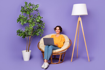Portrait of attractive cheery girl sitting in chair using netbook smm blog post marketing isolated...