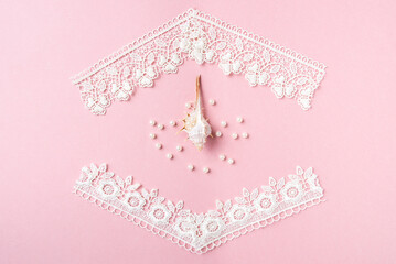 Fototapeta na wymiar white lace, shell and pearls on a pink background