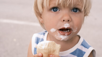 a small child eats white ice cream with great pleasure ice cream on face