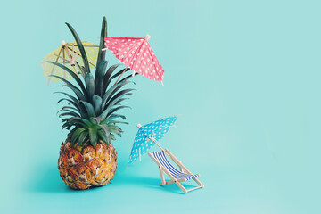 Image with ripe pineapple with parasol and beach chair over blue background. Summer holidays and tropical theme © tomertu