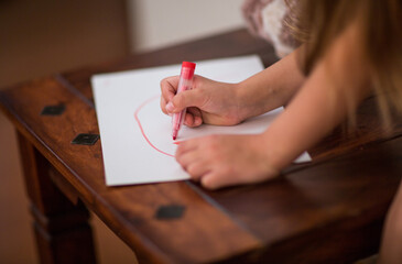 Girl drawing with a red felt-tip pen.