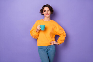 Portrait of charming satisfied person hold coffee cup put hand waist isolated on purple color background
