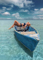 Pretty woman in a bikini sailing in the boat alone in the ocean with clear turquoise water on the beautiful sky background.