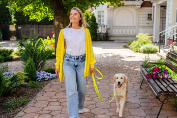happy smiling woman in yellow sweater walking at her house with a dog golden retriever