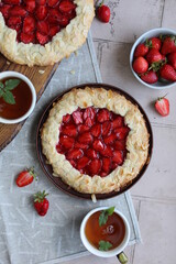 Delicious summer galette with pieces of juicy strawberries. Flat lay with open pies and cups of tea. Summer lunch with berry pastries.