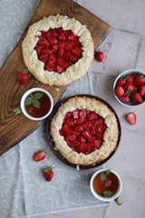 Delicious summer galette with pieces of juicy strawberries. Flat lay with open pies and cups of tea. Summer lunch with berry pastries.