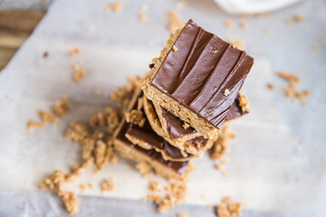 High energy oatmeal bars or squares, made with oatmeal, peanut butter, honey, coconut oil, and cashews, topped with chocolate. Close view and shallow depth of field.