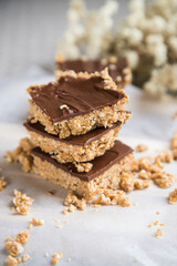 High energy oatmeal bars or squares, made with oatmeal, peanut butter, honey, coconut oil, and cashews, topped with chocolate. Close view and shallow depth of field.