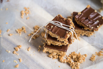 High energy oatmeal bars or squares, made with oatmeal, peanut butter, honey, coconut oil, and cashews, topped with chocolate. Close view and shallow depth of field.