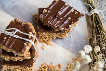 High energy oatmeal bars or squares, made with oatmeal, peanut butter, honey, coconut oil, and cashews, topped with chocolate. Close view and shallow depth of field.