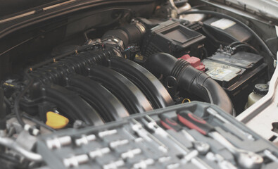 A set of socket wrenches lies on the internal combustion engine of a car in the engine compartment.