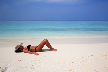 Fototapeta na wymiar Girl lying on the beach at the seashore, Biyadhoo island, Maldives