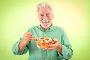 Portrait of cheerful senior man ready to eat a fresh summer fruit salad, elderly grandfather...