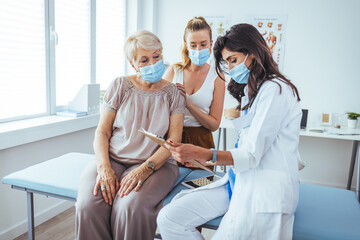 Close up of a senior woman and her daughter having a doctors appointment. Professional smiling doctor meeting a senior patient and her daughter at the hospital, medical service concept