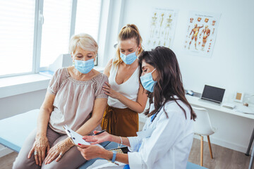 Carring mid adult woman talks with her mom's healthcare nurse. The daughter has her arm around her...